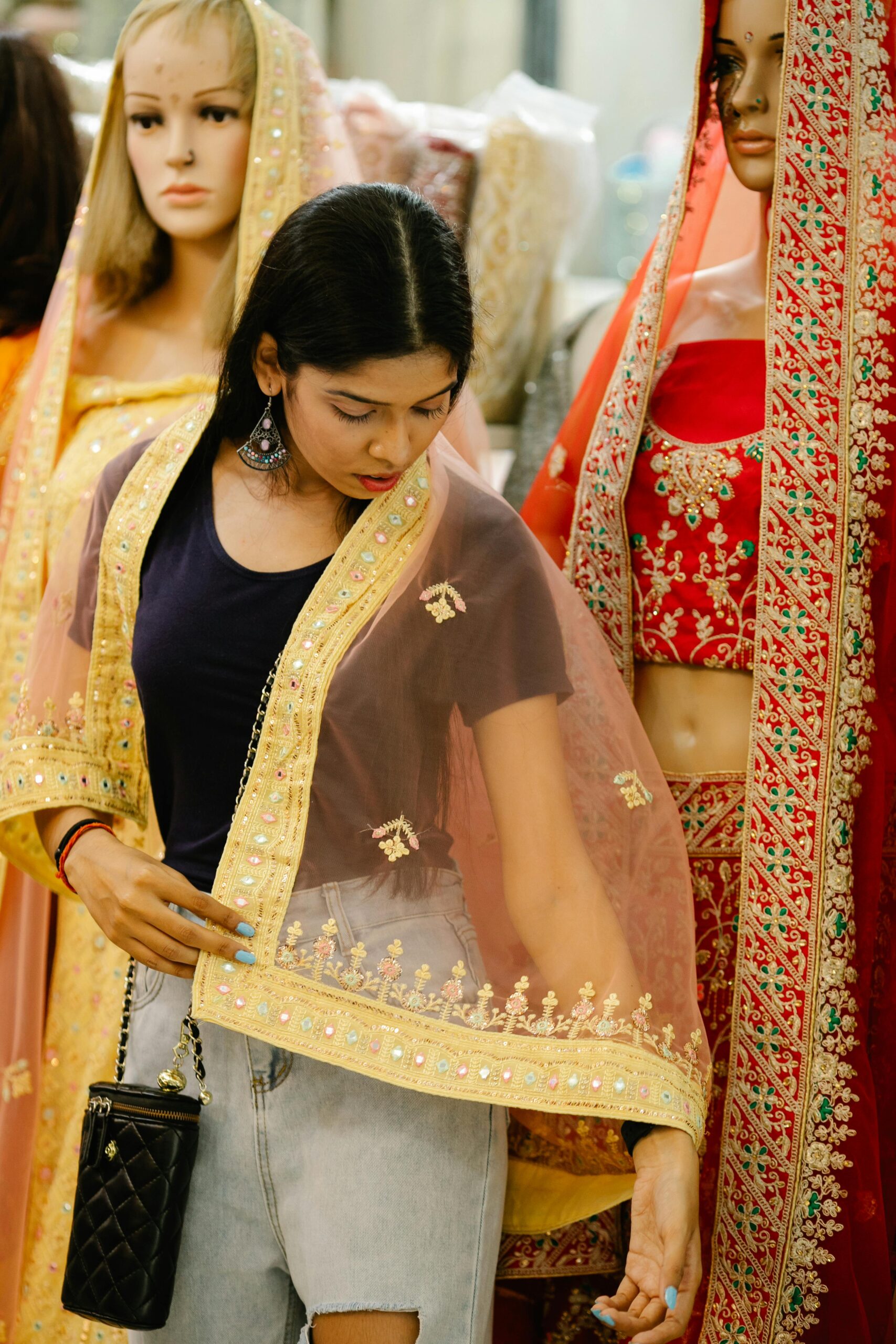 Young woman trying traditional Indian wear in a clothing store with mannequins.